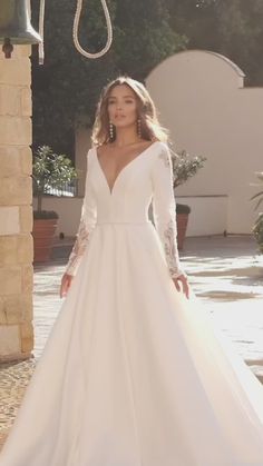 a woman in a white wedding dress standing on a stone walkway with her hands on her hips