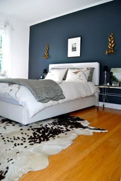 a white bed sitting on top of a hard wood floor next to a blue wall