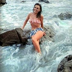 a woman in a bathing suit standing on some rocks