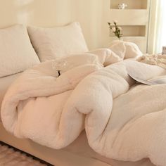 an unmade bed with white sheets and pillows