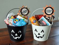 two buckets filled with candy sitting on top of a wooden table