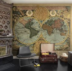 an old world map on the wall in a living room with leather chairs and suitcases