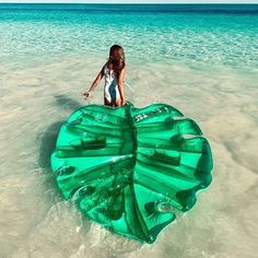 a woman standing in the water with a large green object floating on top of it