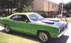 a green and black car parked in front of a house