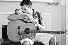 a man holding a baby while sitting on top of a guitar