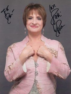 a woman in a pink jacket posing for the camera with her hands on her chest