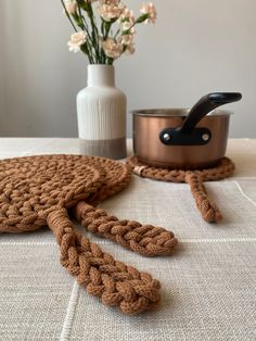 a crocheted pot holder sits on a table next to a vase with flowers