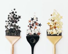 three hairbrushes with stars on them are lined up against a white wall and one has a black holder