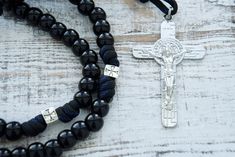 Prepare to embark on a sacred journey of unwavering devotion with our "Solemn Crusader" Paracord Rosary. Crafted for those who seek both strength and grace in their faith, this rosary is a symbol of profound reverence and militant devotion. The "Solemn Crusader" Paracord Rosary is shrouded in solemnity. Its black paracord, as dark as the midnight vigil of a crusader, forms a durable and sturdy foundation, ready to withstand life's challenges. The 12mm shiny black Hail Mary beads exude strength, Adjustable 108 Beads Cross Rosary, Spiritual Crucifix Rosary For Blessing, Crucifix Rosary With 8mm Beads For Meditation, Adjustable Spiritual Rosary With Miraculous Medal, Adjustable Rosary With Miraculous Medal And Crucifix, Adjustable Black Cross Rosary, Traditional Black Rosary With 8mm Beads, Adjustable Black Rosary With Cross, Paracord Rosary