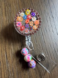 This bold bright flower badge or happy face badge reel  is showing off some fun perfect and cutesy.  These make super fun and useful gifts for any person in any profession. A great gift choice for nurses, medical staff, office staff, and anyone who is required to wear a badge. Hand made with glitter, resin, and design rhinestones rim bottle cap with resin to make it waterproof. Each design is handmade so each badge we make will look slightly different than the next.    Bead charm can be made custom if you would like different colors please message me. Colors of beads will be randomly selected if no choice is made.  Indoor and outdoor photos to show details.  TERMS AND CONDITIONS  By purchasing this item, you acknowledge that you have read the listing description in full and that you agree Rhinestone Badge Reel Diy, Customizable Fun Badge Reel For Gifts, Cute Personalized Badge Reel For Gifts, Fun Pink Badge Holders For Gift, Personalized Cute Badge Reel For Gift, Novelty Pink Badge Holder For Birthday, Customizable Silver Badge Reel Gift, Customizable Silver Badge Reel As Gift, Fun Pink Badge Reel For Gift