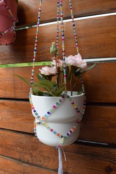 a hanging planter with beads and flowers in it