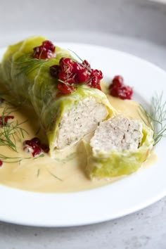 a white plate topped with food covered in sauce and garnished with cranberries