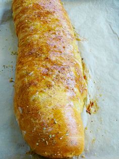 a long loaf of bread sitting on top of a piece of waxed parchment paper