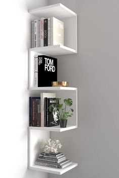 a white shelf with books and plants on it