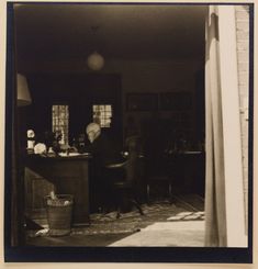 an old black and white photo of a man sitting in a chair at a desk