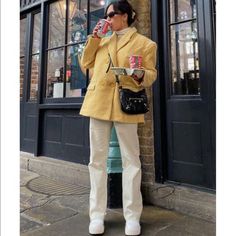 a woman standing on the sidewalk drinking from a cup