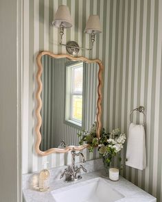 a white sink sitting under a bathroom mirror next to a wall mounted faucet