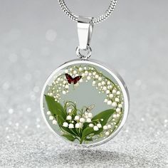 This May Birth flower Necklace features a delicate and beautiful butterfly charm, paired with the delicate and elegant Lily of the Valley flower, the birth flower for the month of May. Created with our patent-pending design, this necklace is made of high quality surgical steel with the option of an 18k gold finish for added luxury. This necklace is the perfect keepsake for yourself or a loved one, and can be customized with a special photo of your choice. You can also opt for custom engraving on Flower Shaped Butterfly Charm Jewelry As Gift, Flower Butterfly Charm Jewelry Gift, Flower-shaped Butterfly Charm Jewelry Gift, Flower Shaped Butterfly Charm Jewelry Gift, Elegant Spring Jewelry With Butterfly Charm, Elegant White Pressed Flower Necklace, Spring Butterfly Charm Jewelry Gift, Silver Necklace For Spring Gift, Silver Necklaces For Spring Gift