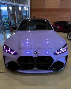 the front end of a purple car in a showroom