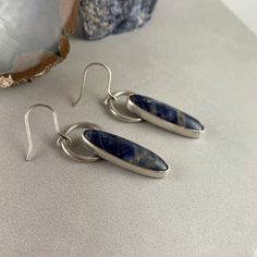 Deep indigo blue sodalite earrings handcrafted and set in sterling and fine silver. These are gorgeous and pair well with outfits for day and evening events. Handmade 5/8" at widest point Hangs from ear: 2 inches Materials: sterling and fine silver, sodalite Nickel-free Closure: ear wire in sterling silver It is believed that sodalite is the ultimate calming crystal and assists with mind-emotion balance and impulse control. It is also said to encourage restful sleep. Blue Sterling Silver Earrings With Polished Finish, Modern Sapphire Sterling Silver Earrings, Handmade Sodalite Jewelry As Gift, Sterling Silver Blue Earrings With Faceted Beads, Silver Sodalite Jewelry With Natural Stones, Silver Sodalite Jewelry For Healing, Elegant Round Sodalite Jewelry, Blue Sodalite, Indigo Blue