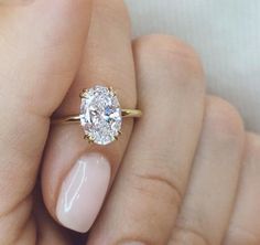 a woman's hand holding a ring with a large diamond on the middle of it