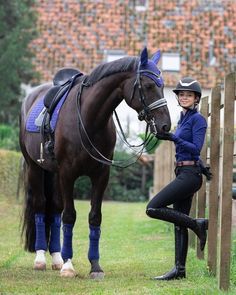 a woman standing next to a brown horse