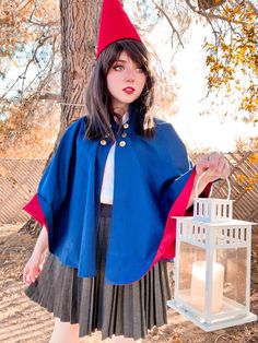 a woman in a blue cape holding a white lantern