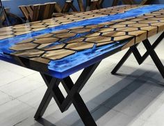 a table that is made out of wood and has blue paint on the top, with chairs in the background