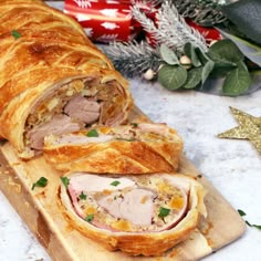 a ham and cheese pastry cut in half on a cutting board next to christmas decorations