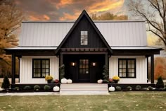 a black and white house with pumpkins on the front porch, and trees in the background