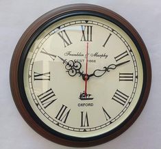 a clock with roman numerals on the face and hands is hanging from a wall