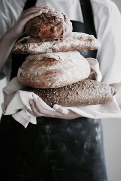 a person holding three loaves of bread on top of each other in their hands