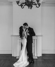 a bride and groom kissing in front of a chandelier