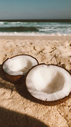 two coconuts are laying on the sand at the beach