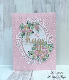 a card with the word hugs on it and some flowers in front of it that says hugs