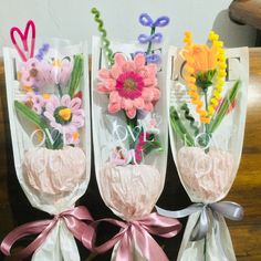 three vases with flowers in them and ribbons tied around the stems on each side