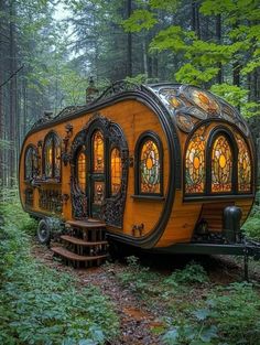 an orange and black tiny house in the woods with stained glass windows on it's sides