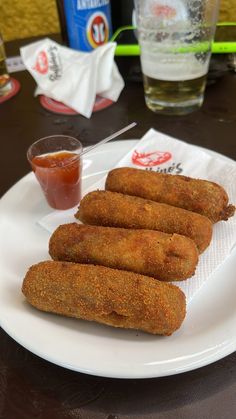 four fried food items on a plate with ketchup and condiments next to it