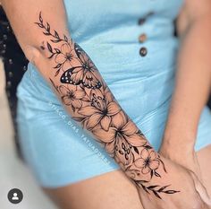 a woman's arm with flowers and butterflies tattooed on the side of her arm