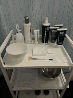 a white table topped with lots of items and a bowl on top of it next to a sink