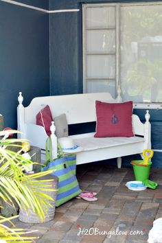 a white couch sitting on top of a brick floor next to a blue wall and potted plants