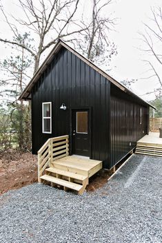 a small black cabin with stairs leading up to it