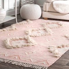 a pink rug with tassels on the floor in a white living room area