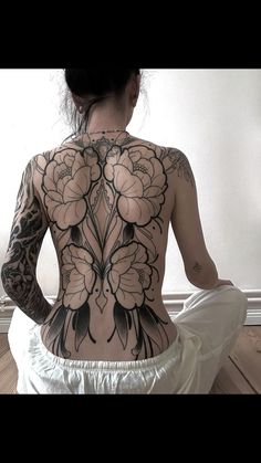 a woman is sitting on the floor with her back tattoo