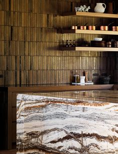 the counter top is made out of white and brown marble, with shelves above it