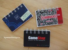 three small notebooks sitting next to each other on a wooden table with a notepad