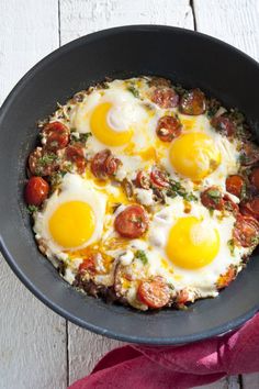 an iron skillet filled with eggs on top of a table next to other plates and utensils