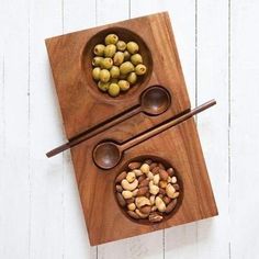 two bowls filled with nuts on top of a wooden cutting board next to chopsticks