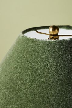 a green lamp shade with a gold ball on it