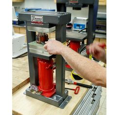 a man is working on a red fire hydrant in a shop with other tools